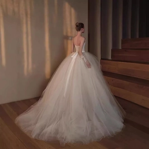 Elegant back view of white lace bridal gown with deep V-back and silk bow on stairs