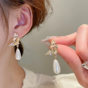 Detail of gold butterfly earrings with sparkling crystals and a drop pearl pendant