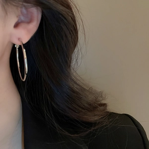 Close-up of minimalist silver hoop earrings worn by a model in a profile view