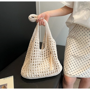 Detail of cream crochet beach tote featuring intricate mesh weave and long fringe tassel
