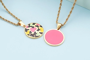 Detail of gold twist chain necklace featuring colorful heart and pink enamel pendants