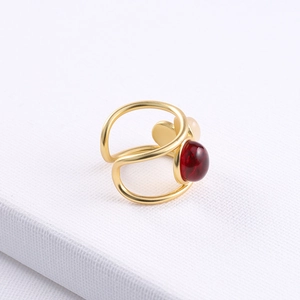 Detail of adjustable gold double-band ring with a red gem and pink heart accent