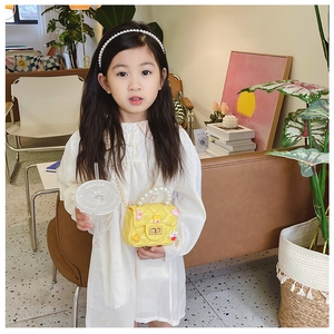 Little girl wearing a yellow cartoon crossbody bag with pearl handle and metal chain strap