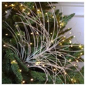 Close-up of white glittered Christmas tree branches with festive bokeh light background