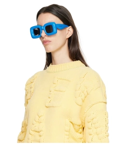 Detail of bright blue puffed frame sunglasses worn with a yellow knit sweater
