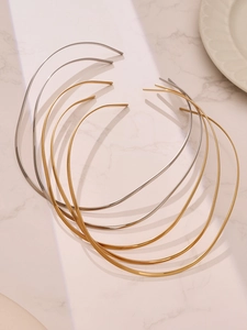 Vue détaillée de colliers rigides minimalistes or et argent sur surface en marbre