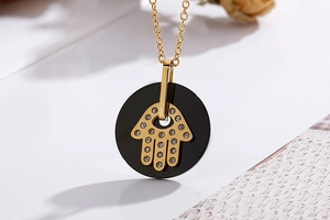 Macro view of gold Hamsa hand pendant featuring black base and sparkling rhinestones