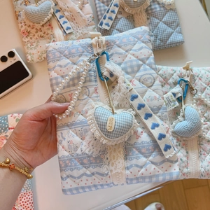 Detail of blue floral quilted makeup bag with lace trim and pearl chain strap handle