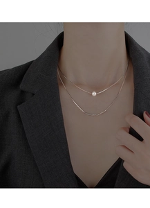 Detail view of layered baroque pearl necklace with silver chain on professional model