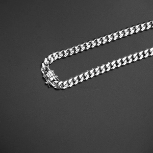 Detail of silver Cuban link necklace featuring a secure square press buckle on black background