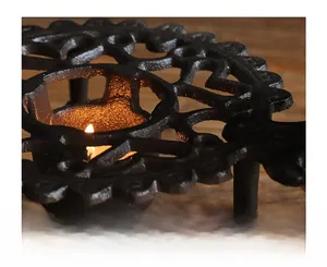 Detail macro view of a vintage cast iron tea warmer base with lit candle inside