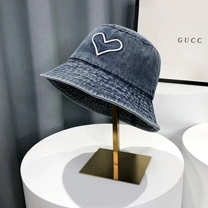 Detail of white heart embroidery and parallel stitching on washed blue denim bucket hat