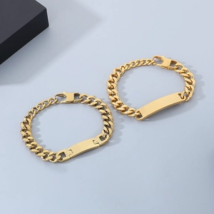 Detail of two golden stainless steel Cuban ID bracelets with engravable blank plates
