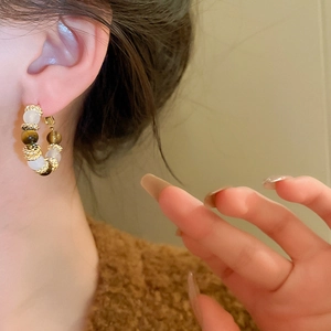 Detail of vintage beaded hoop earring with tiger eye and cat eye stones on model