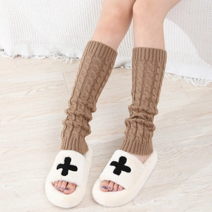 Detail of warm brown cable-knit leg warmers paired with soft white plush slippers