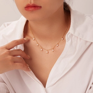 Close-up of elegant 18K gold stainless steel necklace with small pearl tassel pendants