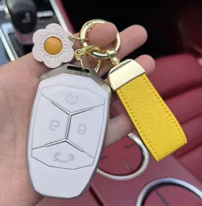 Yellow leather car keychain with daisy charm and gold hardware on red car interior