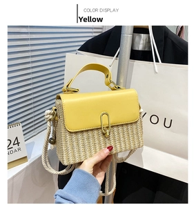 Detail of yellow leather flap and straw woven texture on a large stylish crossbody bag