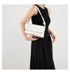 Detail view of a white quilted crossbody bag featuring unique knotted strap details