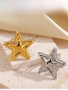 Macro detail of double-layered star stud earrings in polished gold and silver finish