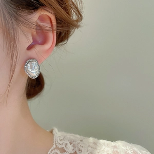 Close-up of irregular baroque pearl earrings with silver metal trim on model's ear