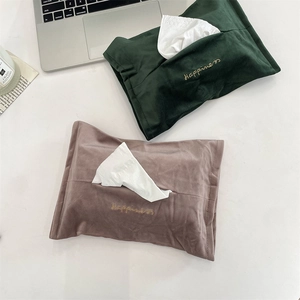 Detail of velvet tissue bags with Happiness embroidery and wavy edges in a home setting