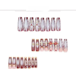 Détails d'ongles French rouges à coller avec strass brillants et breloques de croix dorées