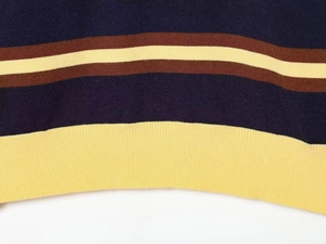 Close-up of striped knit sweater hem with navy blue, brown, and yellow ribbed finish