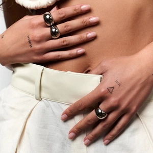 Close-up of a model wearing two chunky silver spherical rings in a modern fashion style