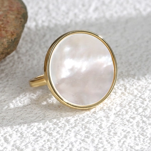 Minimalist gold ring featuring a large round white shell stone on a textured background