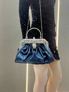 Detail of elegant black pleated evening clutch with sparkling rhinestone trim and chain