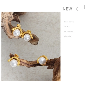 Close-up of elegant gold pearl earrings artfully placed on a dried branch detail