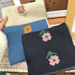 Close-up of knit scarves in beige, blue, and black with floral patterns and soft texture