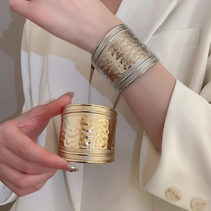 Détail de bracelets manchettes dorés et argentés avec texture martelée et bords perle