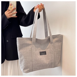 Close-up of grey canvas tote bag showing thick woven texture and black fashion label