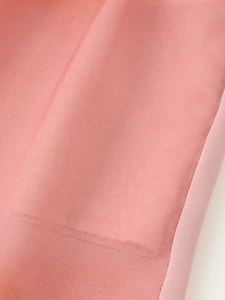 Vue macro détaillée montrant la texture du tissu tie-dye rose et les coutures de la robe