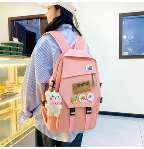 Pink nylon school backpack detail featuring a cute plush bear charm and cartoon badges