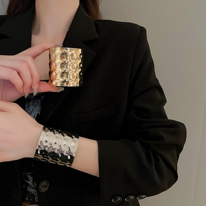 Detailed view of wide hammered metal bracelets in gold and silver finish on wrist