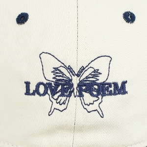 Detailed macro view of blue butterfly embroidery and Love Poem text on beige baseball cap