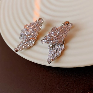 Close-up of silver earrings with marquise-cut zircons in a wing-like leaf pattern