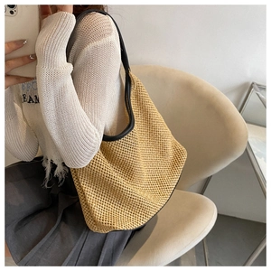 Women's woven shoulder bag in khaki with black leather straps shown on a model