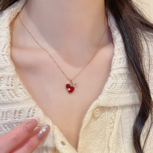 Detail of elegant gold necklace with red enamel gourd and coin charms on a female model