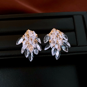 Close-up of golden tassel earrings with marquise crystals on a black display stand