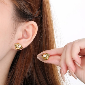 Elegant irregular gold pearl stud earrings showing on ear and held in hand for women