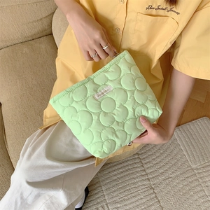 Detail of light green floral quilted makeup bag with zipper and woven label