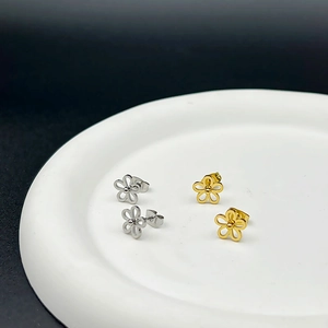 Minimalist titanium steel flower stud earrings in gold and silver set on white ceramic