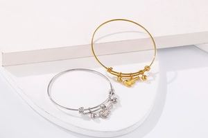 Detail of gold and silver guitar pendant bracelets on white stone stairs