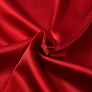 Vue détaillée du satin rouge avec plis élégants en spirale et texture de soie brillante