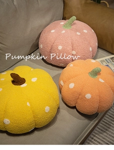 Close-up of pink, yellow and orange plush pumpkin pillows with white polka dots