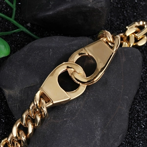Macro shot of gold Cuban link bracelet with dual interlocking buckle on black rock